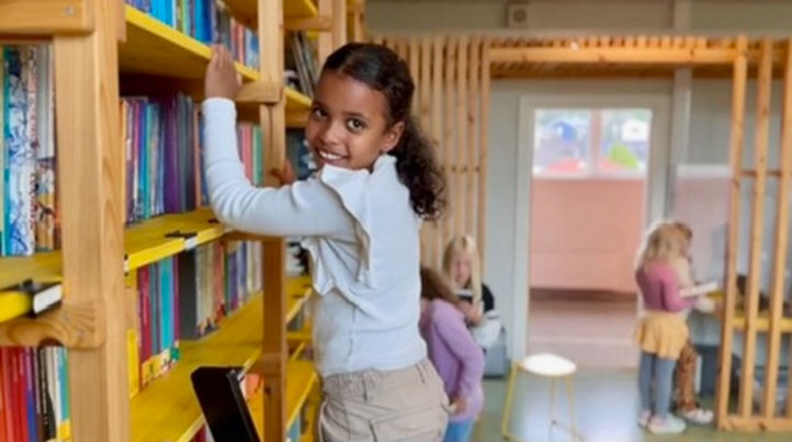 En ung barn som står i et bibliotek En ung barn som står i et bibliotek
